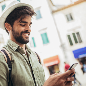 Man smiling outdoors near a museum building looking at his phone