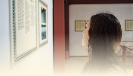 Woman viewing a framed piece on a gallery wall
